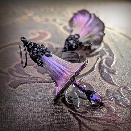 Handmade Iridescent Lucite Flower Earrings in Dark Color Shifting Purple, Fuchsia and Blue, with Gothic Victorian Style Black Metal Filigree photographed on a brown vintage background